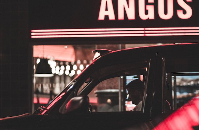 Favor driver waiting outside a restaurant for an order to be ready.