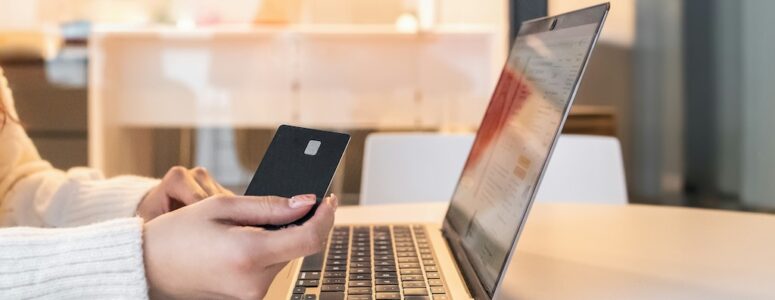 Woman sitting at her laptop with her phone using Fetch to save money.