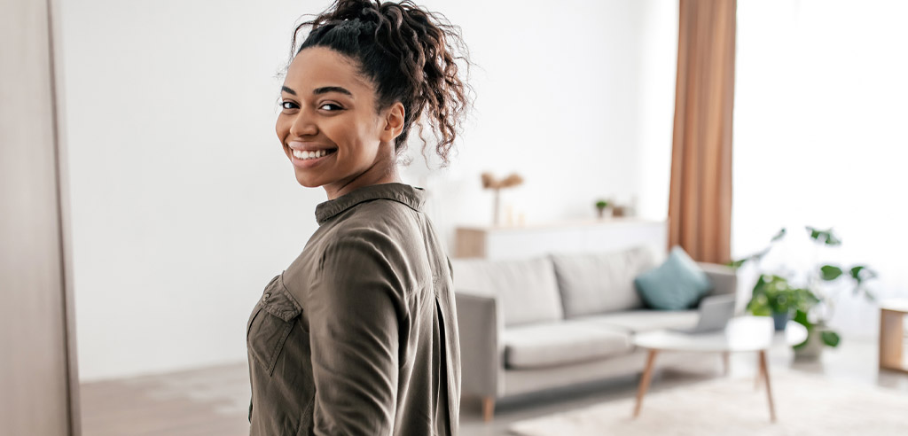 Woman standing in the apartment that she's renting on her own