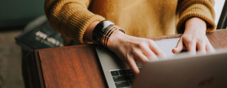 Close view of a freelance grant writer as they work on their laptop.