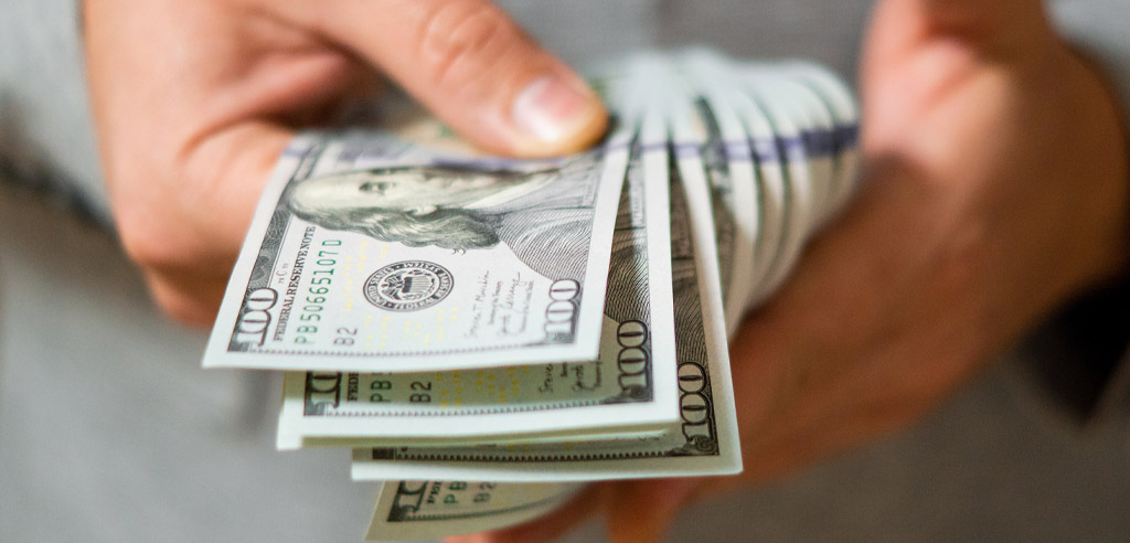 Close view of hands holding hundred dollar bills