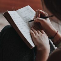 Freelancer writing by hand in their notebook.