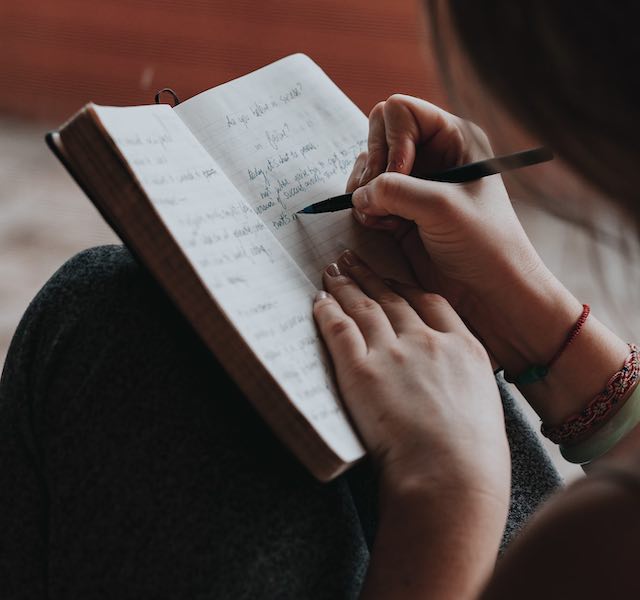 Freelancer writing by hand in their notebook.