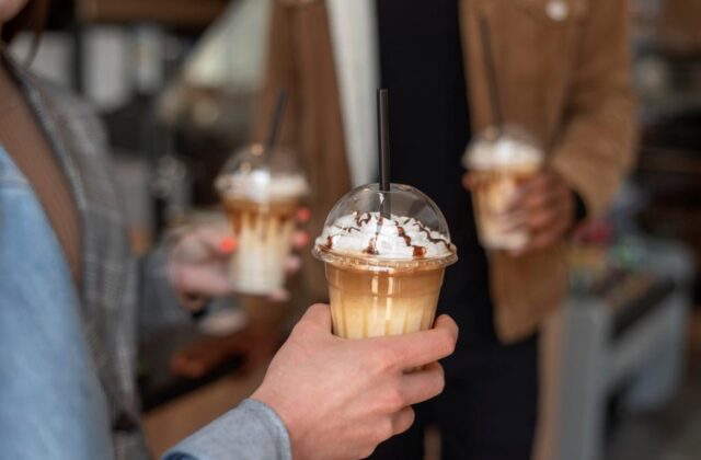 Close view of a man holding a fancy coffee drink.