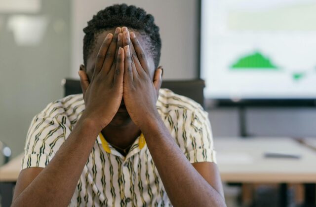 Frustrated employee with his hands over his face.
