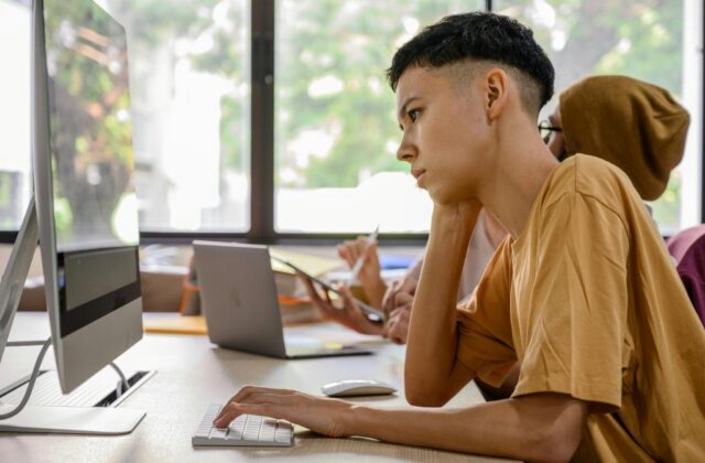 Younger office worker looking bored while working on computer.