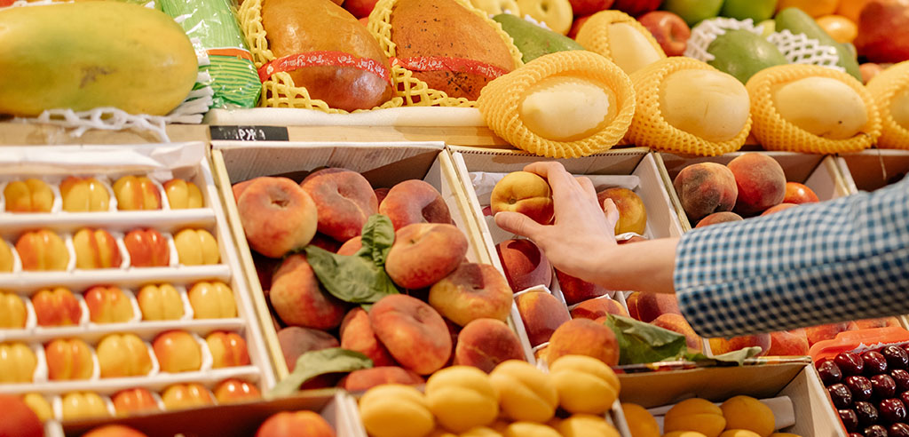 a woman is buying a peach during monthly grocery shopping