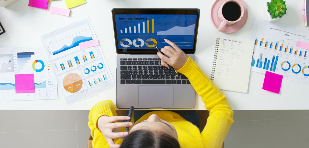 Blogger looking at graphs on various printouts and a laptop screen representing the growth of her blog traffic