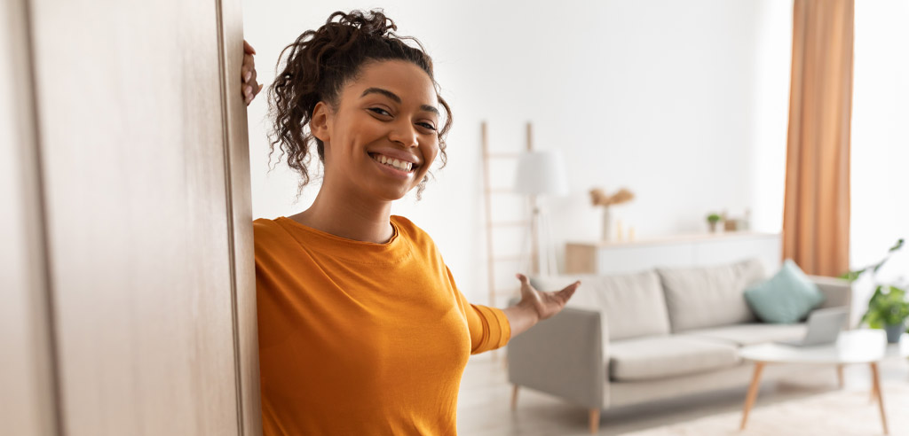 Woman gesturing invitingly into her Airbnb property
