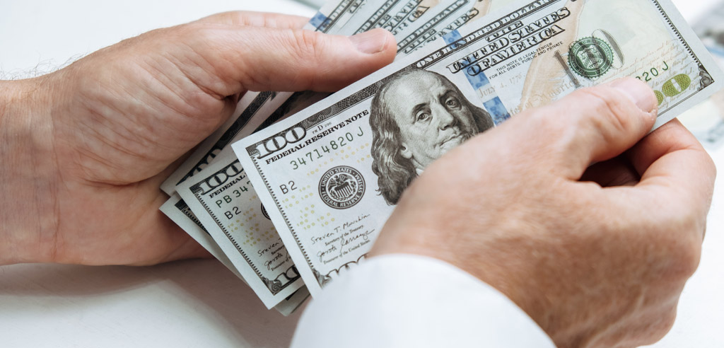 Close view of two hands holding hundred dollar bills