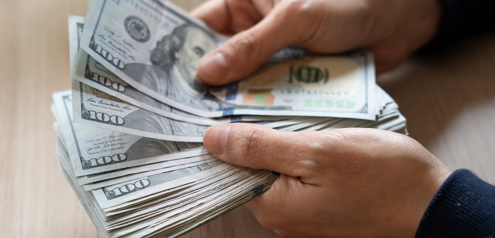 Closeup of person holding a stack of hundred-dollar bills