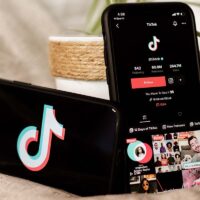 Two smartphones displaying the TikTok logo and profile page for a paid TikToker