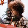 Young person in a music store, earphones around their neck, reading the back of a record