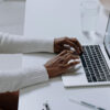 Close view of a blogger at a desk typing on their laptop