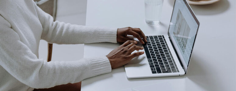 Close view of a blogger at a desk typing on their laptop