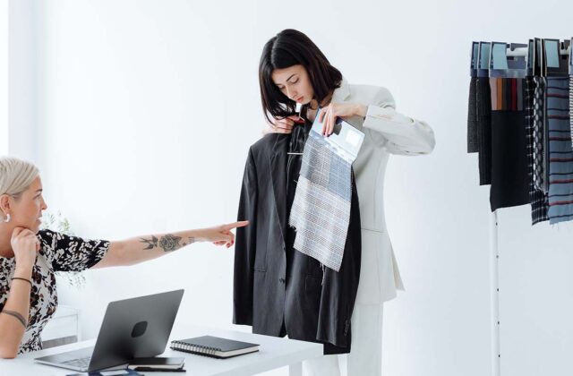 Clothing brand business owner pointing to fabric patterns and giving instructions to an assistant