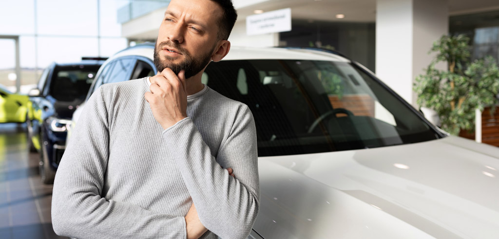 Man standing against his car and contemplating if car wrapping is worth it
