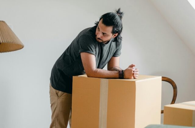 A man resting his arms on a cardboard box.