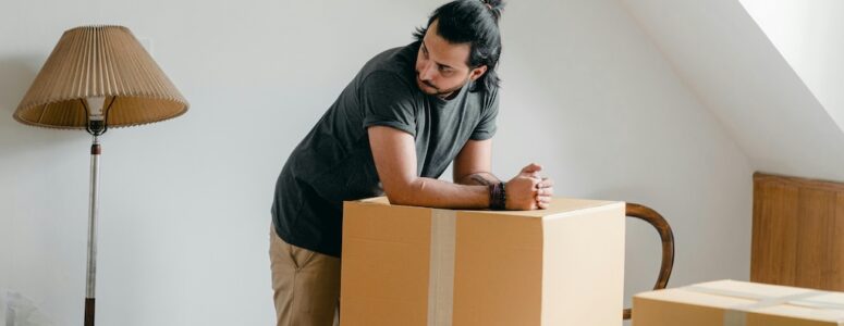 A man resting his arms on a cardboard box.