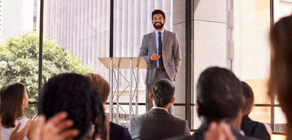 Smiling man receiving applause for his motivational speech