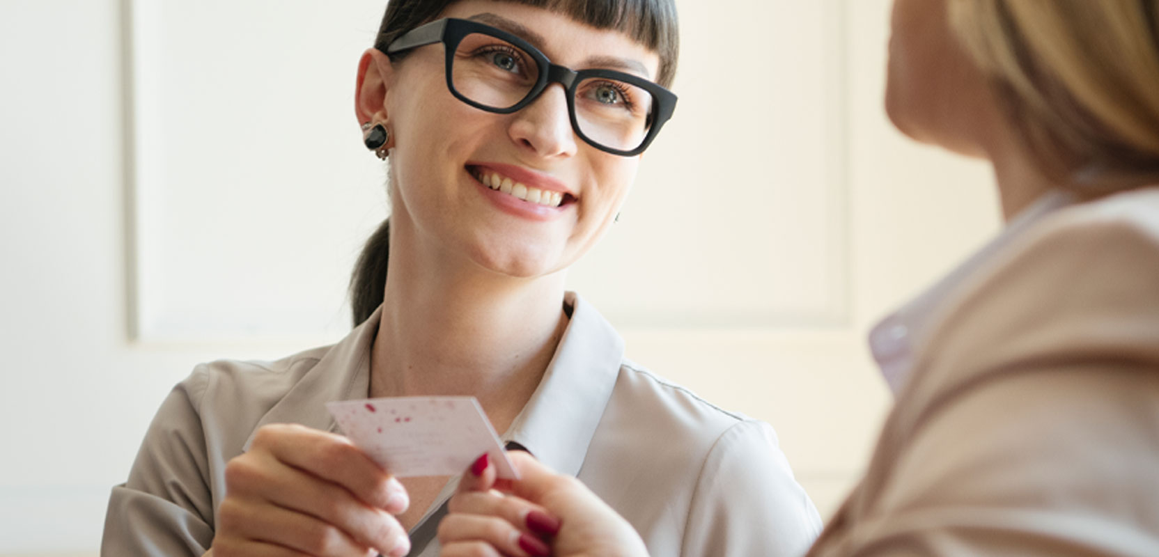 Freelance tutor passing a business card to a woman to advertise her side hustle