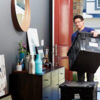 Lugg worker moving packed boxes in a house in preparation for a move.