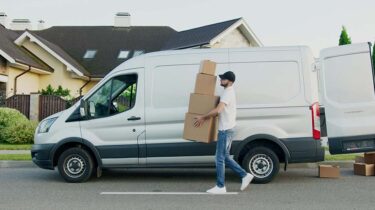 Professional mover carrying boxes outside a moving van.
