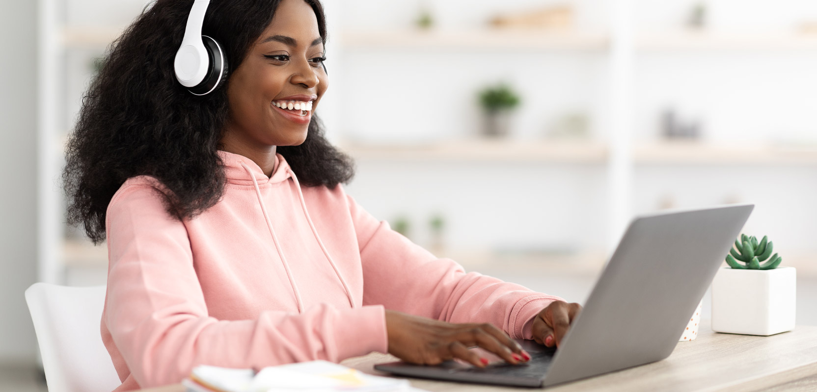 Freelance transcriptionist listening to headphones and working at a laptop to get her transcription certification