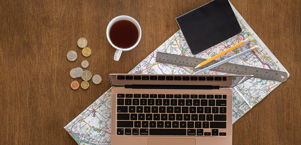 Laptop and map on a table next to a pile of change and a mug