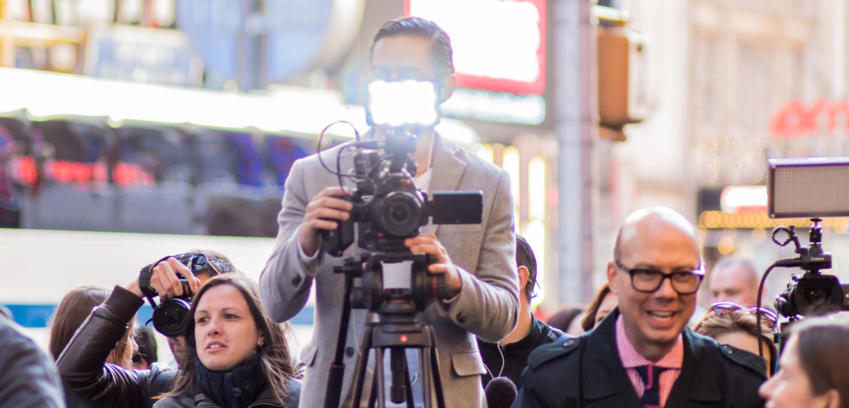 Paparazzo standing behind a camera in a crowd of other photographers
