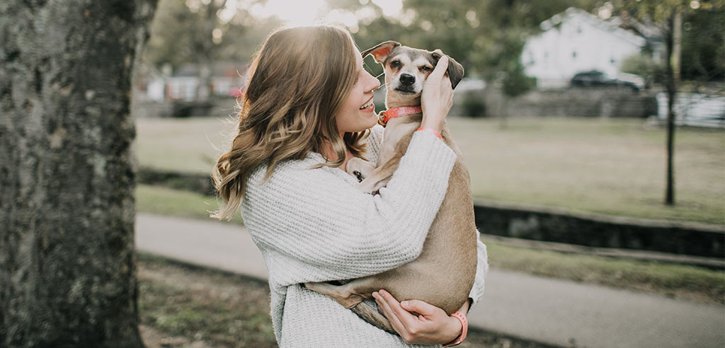 a pet sitter is hugging a dog
