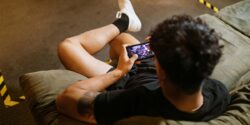 Man sitting in a chair betting on a mobile game on his smartphone.