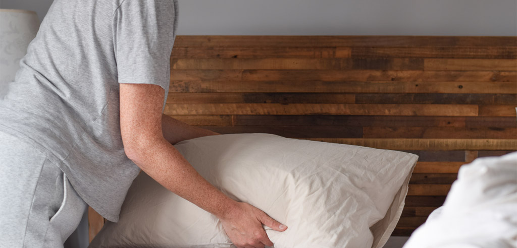 Person adjusting the pillows in their Airbnb rental