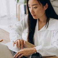 Job-hunter sitting and using her laptop to access Remote.co and look for gigs.