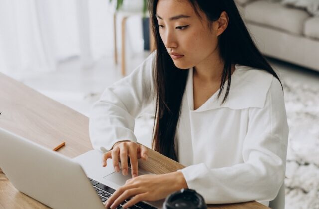 Job-hunter sitting and using her laptop to access Remote.co and look for gigs.