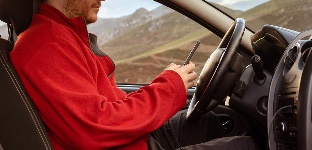 DoorDash driver sitting in his car looking at his phone