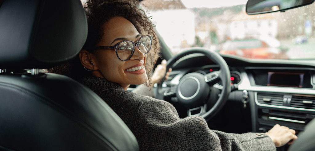 Rideshare driver turning around in her seat and looking backwards while smiling