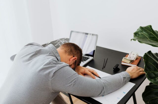 A frustrated employee who experiences quiet firing resting their head on the desk.