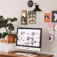 Remote work station for selling handmade items from home, featuring a desk, computer, and handmade cards pinned to the wall