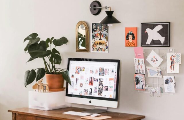 Remote work station for selling handmade items from home, featuring a desk, computer, and handmade cards pinned to the wall