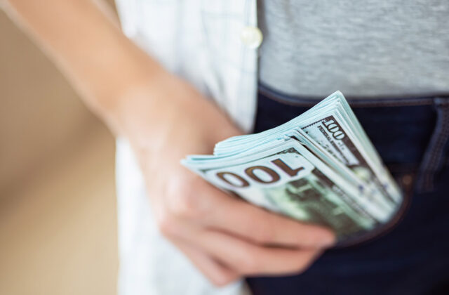 Close view of someone holding a stack of hundred-dollar bills