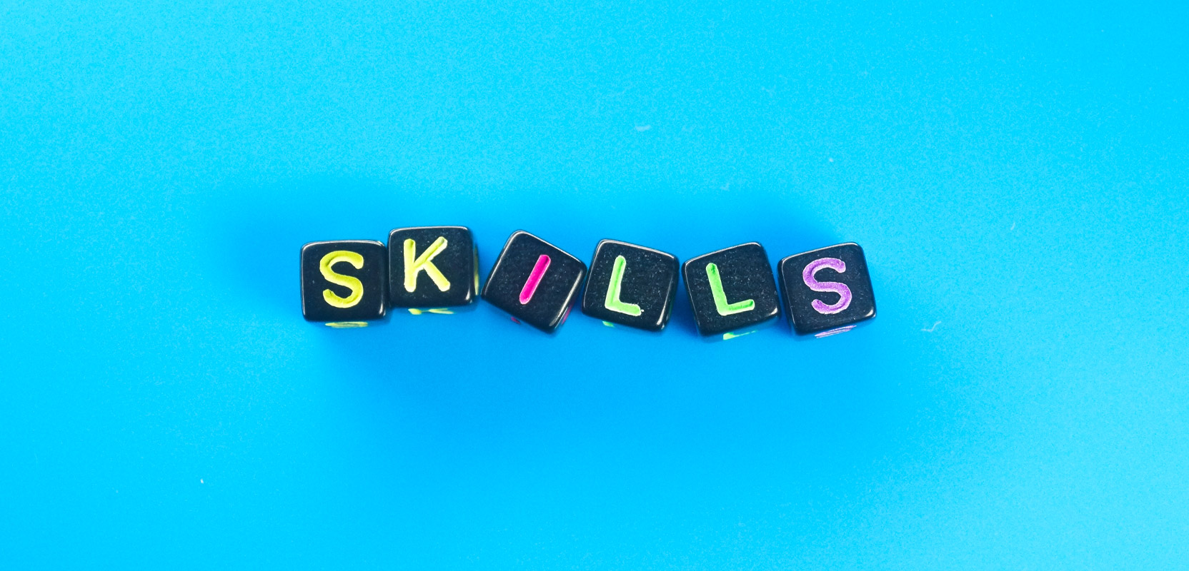 Dice-like cubes with letters on them spelling out the word Skills against a blue background