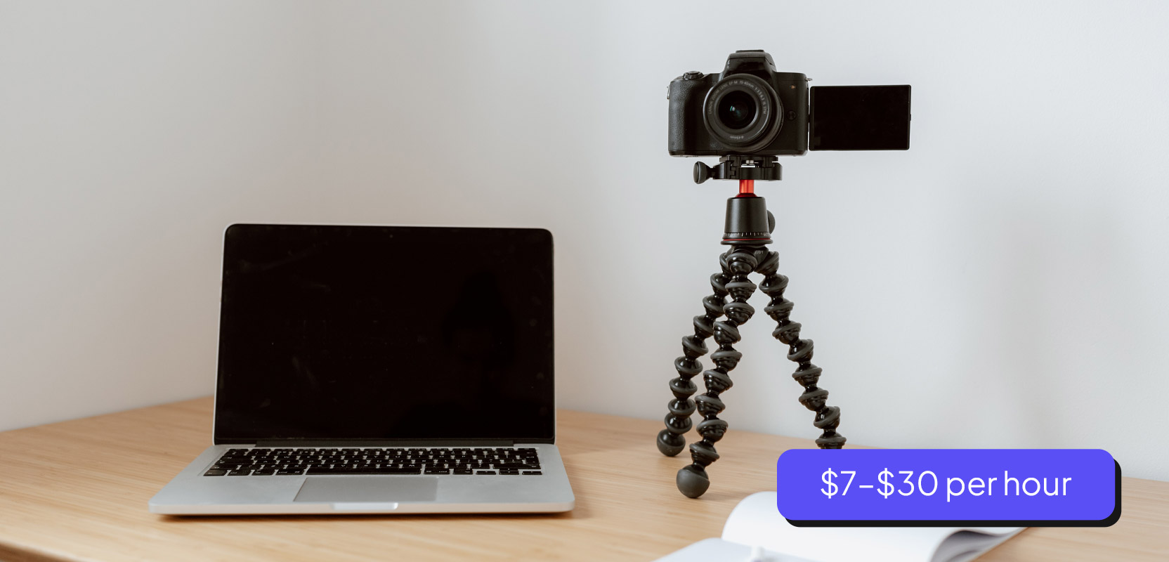 Laptop sitting on desk next to a camera representing a blogging side hustle