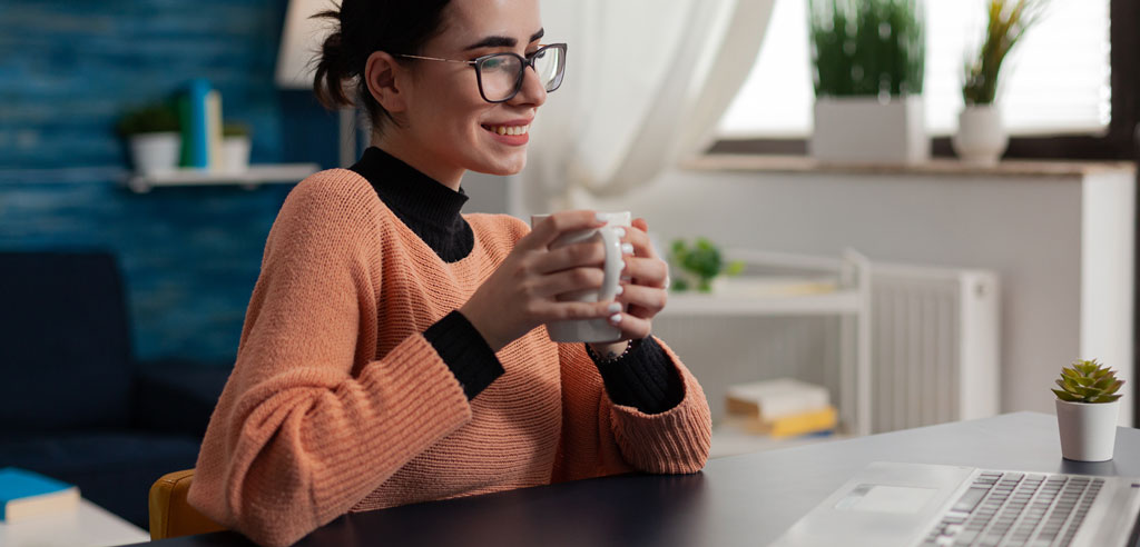 Female freelancer drinking coffee and working on her laptop