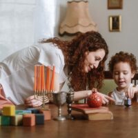 App-based babysitter watching after a young child playing with a dreidel at home