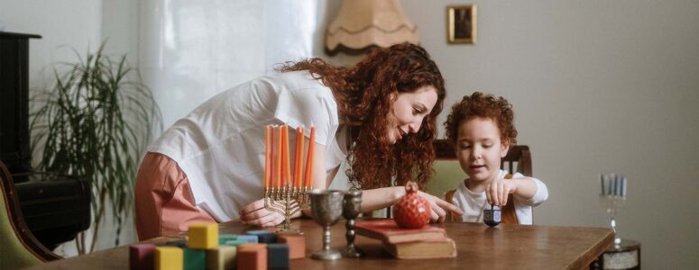 App-based babysitter watching after a young child playing with a dreidel at home