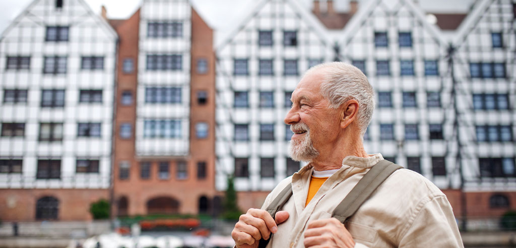 Older tour guide standing in front of a landmark before introducing it