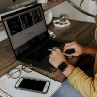 Close view of a virtual assistant at her desk with her hands on her laptop, representing virtual assistant skills.
