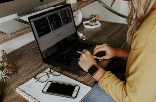 Close view of a virtual assistant at her desk with her hands on her laptop, representing virtual assistant skills.