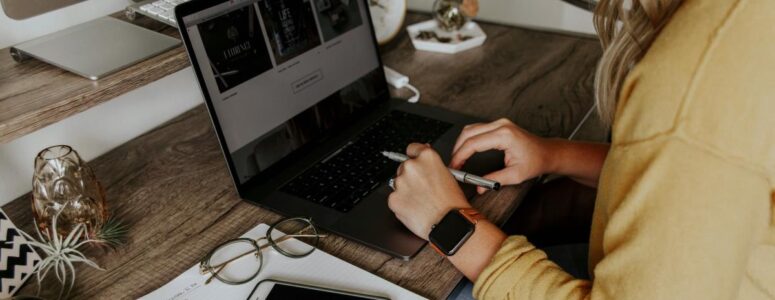 Close view of a virtual assistant at her desk with her hands on her laptop, representing virtual assistant skills.
